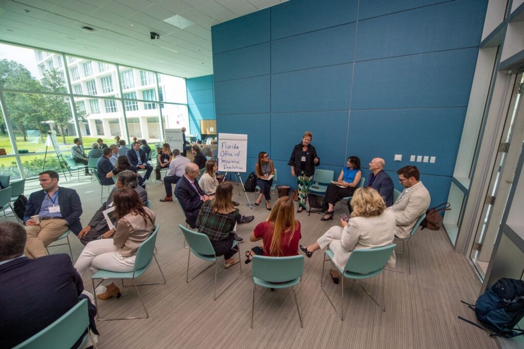 Photo of group conversation at the Miami Property Insurance Strategy Forum. In this photo, participants are in discussion with representatives from the Florida Office of Insurance Regulation.